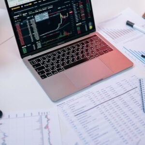 Laptops on a desk displaying stock market charts and financial documents.